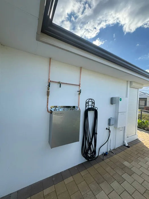 Whole house water filter installed outside near a wall