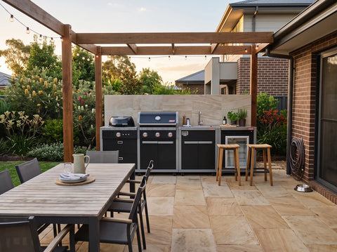 Coleman Revolution modular outdoor kitchen with BBQ, sink and fridge units set up under a pergola