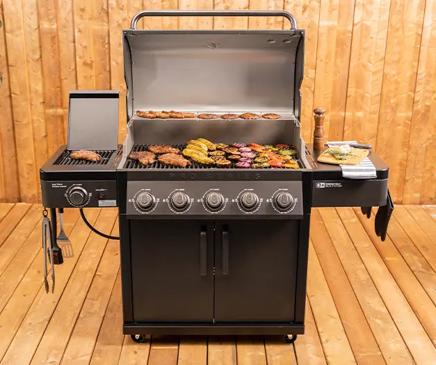 Coleman Pro Series bbq with side burner grilling vegetables and corn on the open lid