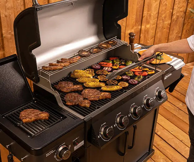 Coleman Pro Series bbq with side burner, close-up of tongs turning food on the grill